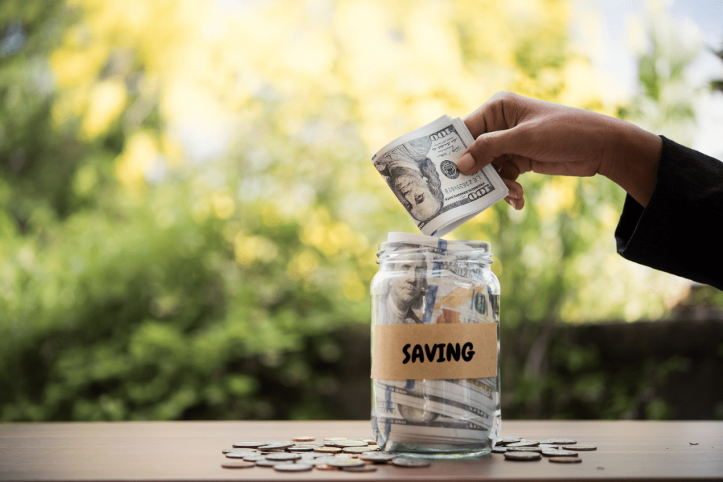 Hand putting money in saving jar representing good money habits