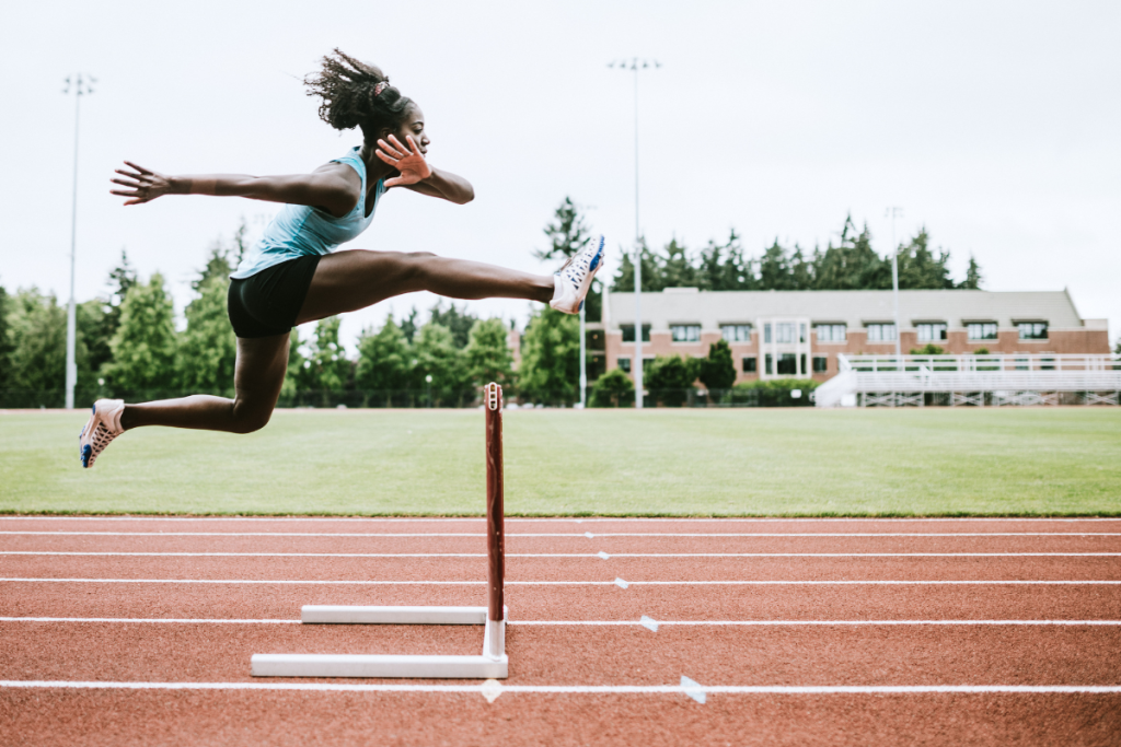 Woman jumping hurdles representing obstacles to achieving goals